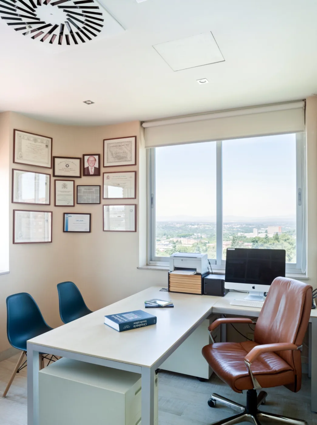Despacho de consulta con pared de diplomas y vistas — formación y trayectoria del equipo